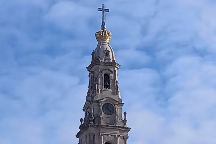 Close-up of the iconic bell tower of the Sanctuary of Fatima against a vibrant blue sky on a private tour.