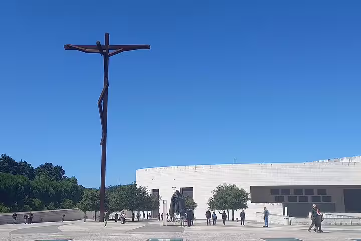 Modern crucifix sculpture under blue sky at Fatima Sanctuary on Tomar-Coimbra and Fatima-Nazare-Obidos tour.