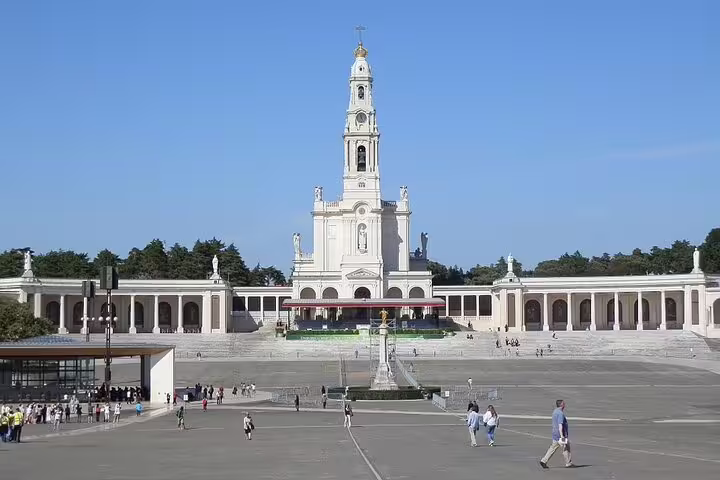 View of Fatima Sanctuary's grand facade under a clear sky, a key highlight of the Fatima and Nazaré tour from Lisbon.