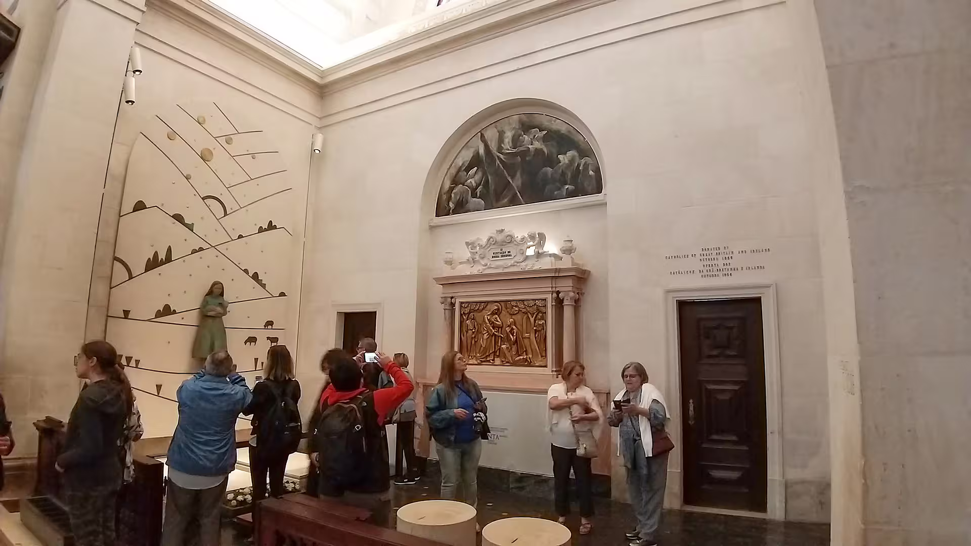 Visitors explore the interior of Fátima Sanctuary, admiring religious artwork and sculptures on a private guided tour.