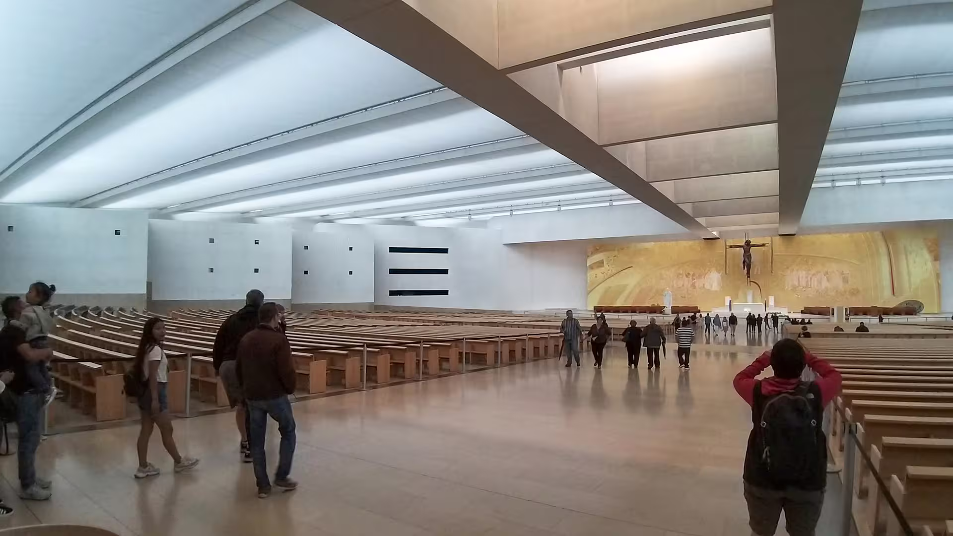 Visitors explore the modern interior of the Fátima Sanctuary, highlighting its spacious design and religious significance.