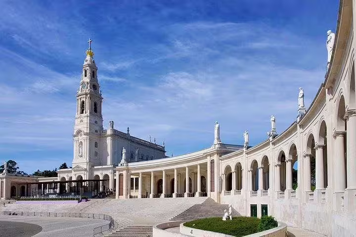 Majestic view of the Sanctuary of Fátima with its iconic colonnades under a clear blue sky.