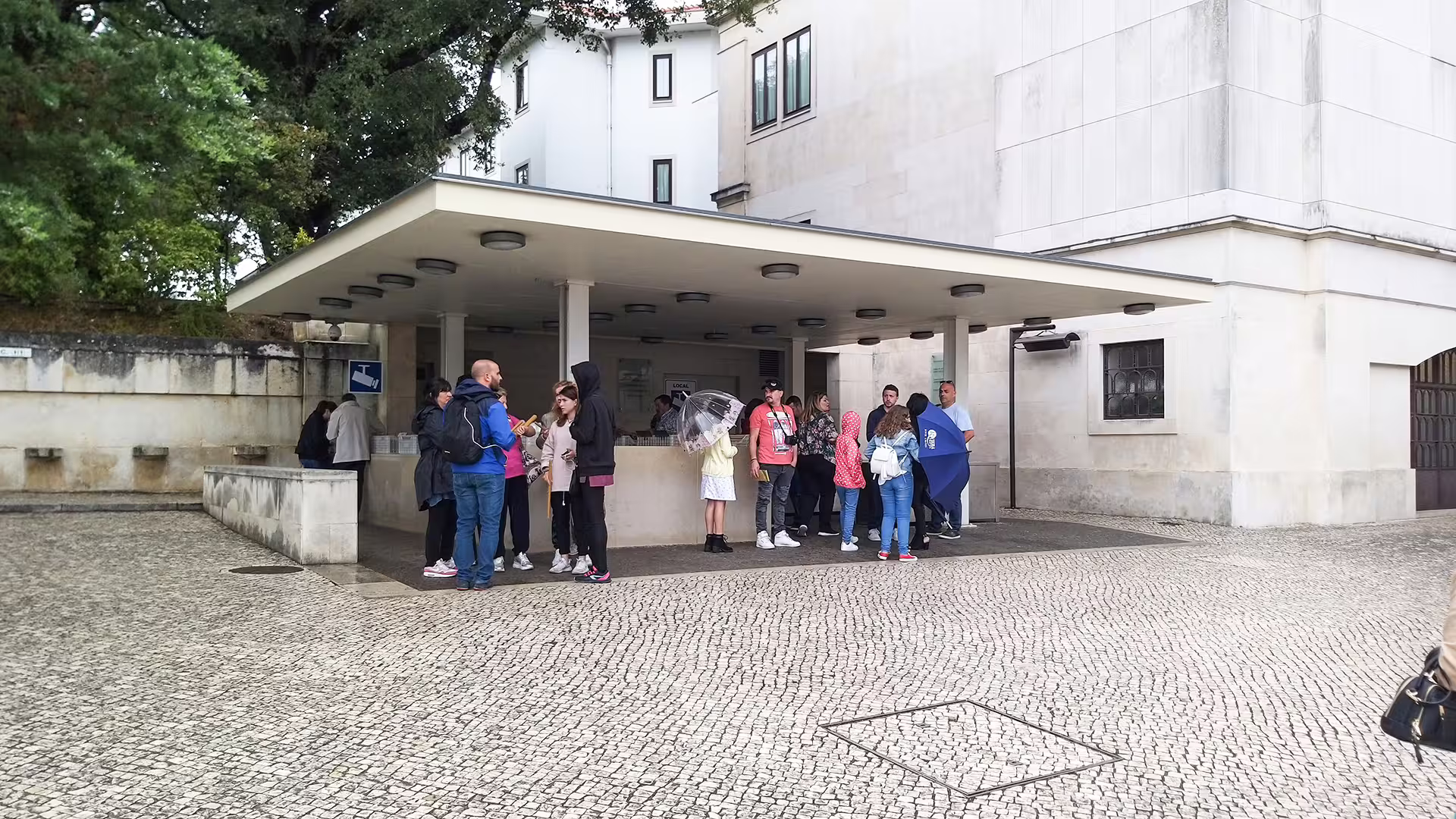 Group of tourists gather under a canopy at Fátima Sanctuary entrance, preparing for a private tour to the Little Shepherds Houses.