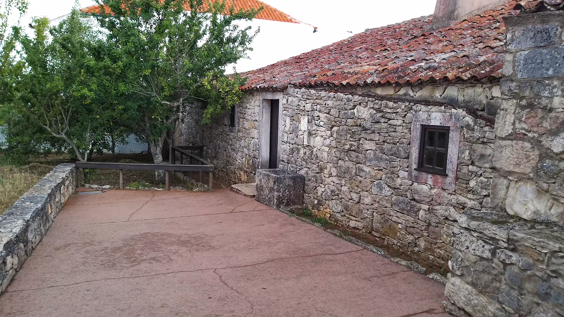 Rustic stone house surrounded by lush greenery, part of the Little Shepherds Houses tour near Fátima Sanctuary in Portugal.