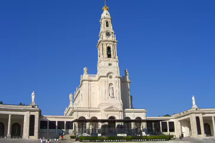 Majestic view of Fátima Sanctuary under a clear blue sky, highlighting its spiritual significance and architectural grandeur.