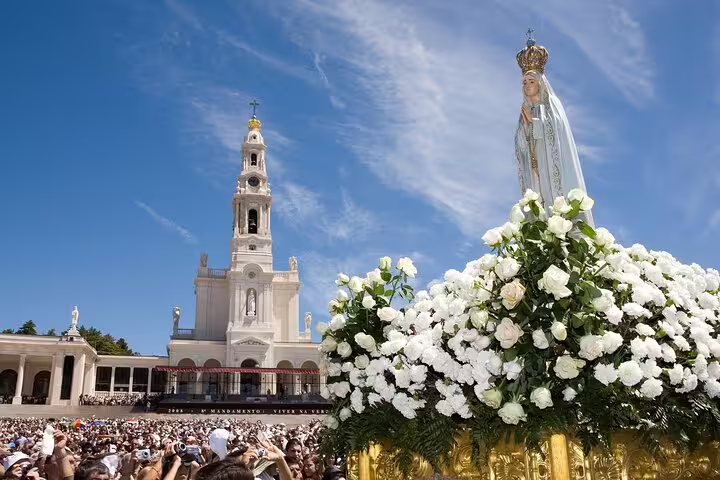 Pilgrims gather at Fatima Shrine with Our Lady of Fatima statue and basilica, Portugal pilgrimage destination.