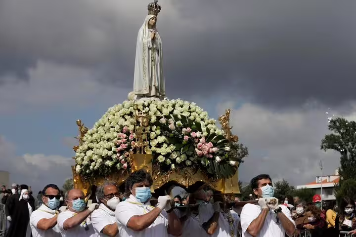 Devotees carry the statue of Our Lady of Fatima surrounded by flowers during a procession at the shrine.