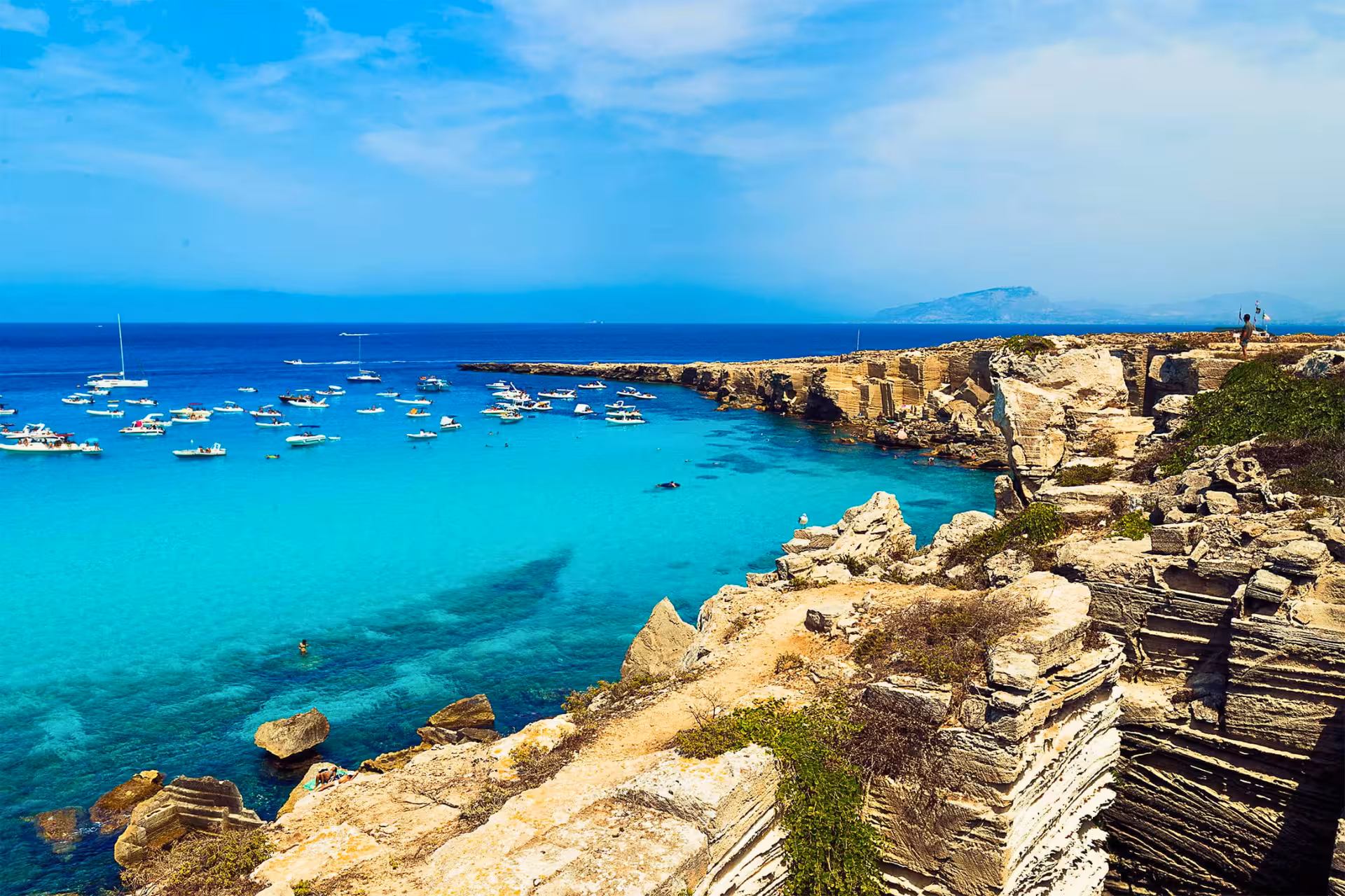 Panoramic Favignana bay with boats and limestone cliffs, Egadi Islands dinghy excursion from Trapani