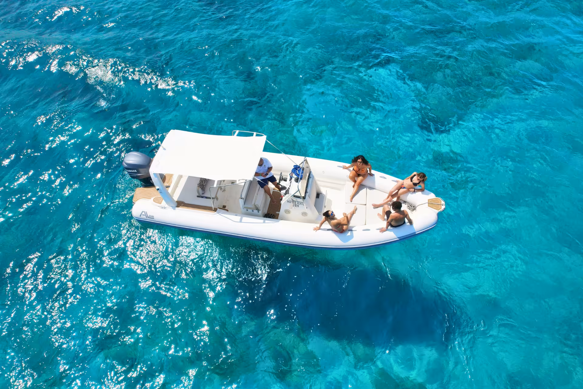 Aerial view of dinghy in turquoise water, guests relaxing on Egadi Islands tour to Favignana and Levanzo from Trapani