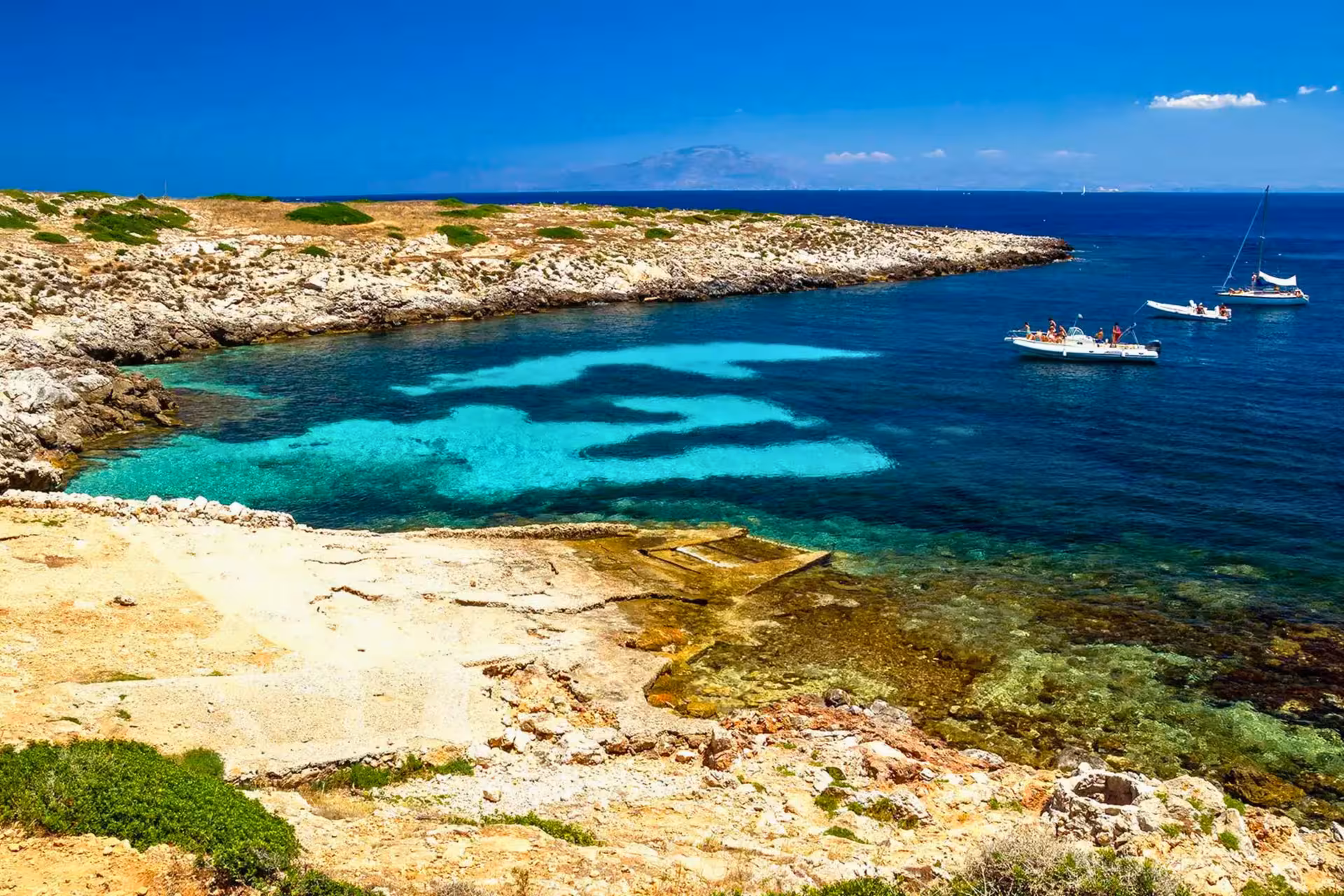 Turquoise bay on Favignana with boats anchored, Egadi Islands excursion from Trapani by boat with lunch