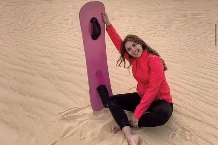 Traveler posing with sandboard on Fayoum desert dunes, Cairo day trip with dune thrills and Magic Lake