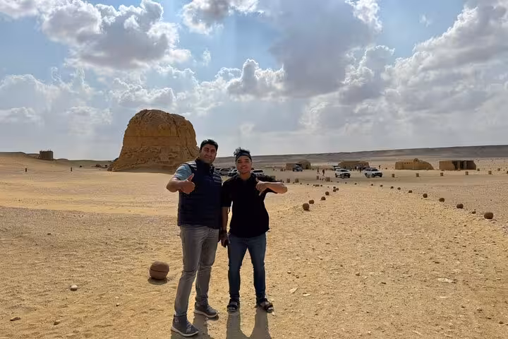 Guests posing by a desert monolith in Fayoum Oasis on a private full-day tour from Cairo with 4x4 safari