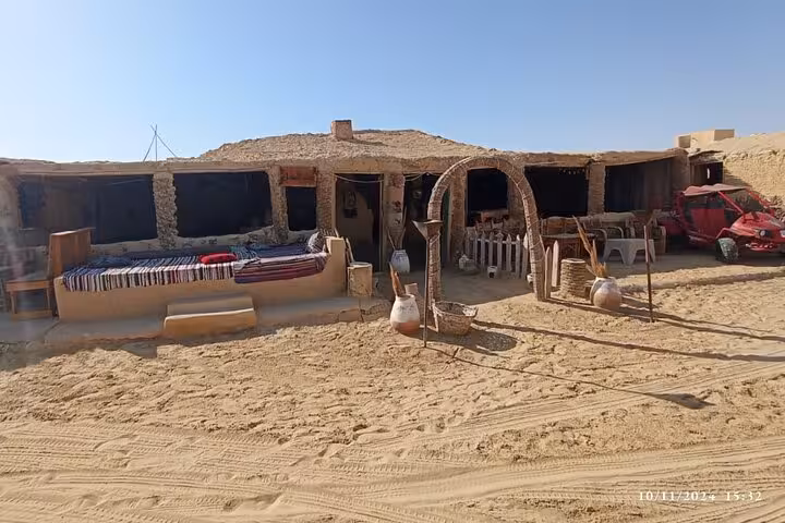Rustic stone lodge with woven rugs and pottery in Fayoum Oasis, offering authentic desert experience on private tour.