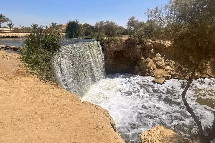 Small waterfall on a Fayoum oasis canal, desert cliffs and palms on the Fayoum nature and history tour