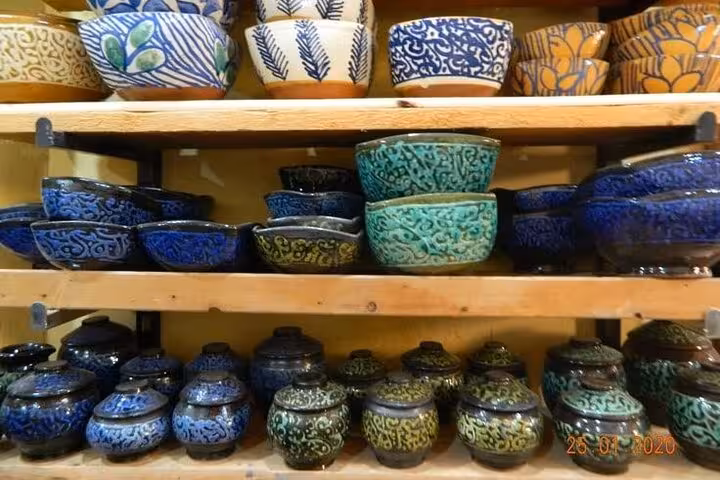 Handcrafted Fayoum pottery bowls and jars on shelves, artisan ceramics stop on Cairo Fayoum Oasis tour