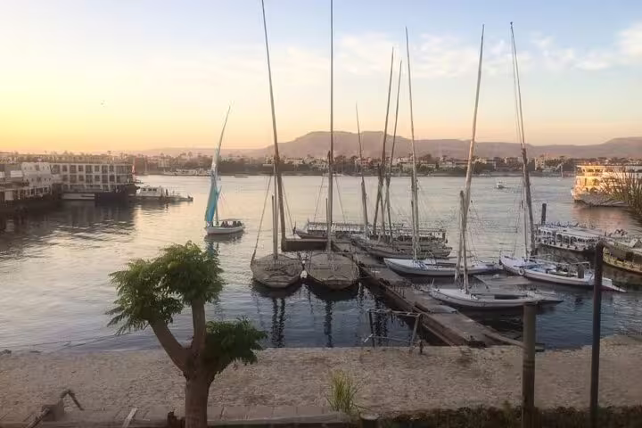 Felucca boats moored on the Nile in Luxor at sunset, serene river view for a classic sailing tour