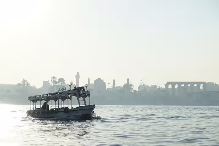 Motorboat cruising the Nile River in Luxor with temple skyline at sunset, scenic river tour experience