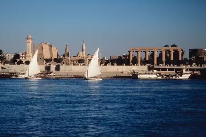 Felucca sailing past Luxor temples on the Nile River, classic sunset felucca ride with ancient views