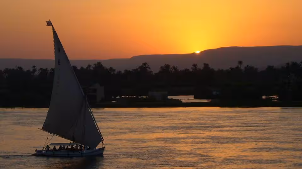 Traditional felucca sailboat cruising the Nile at sunset in Egypt, scenic Nile Adventure felucca cruise with golden river views