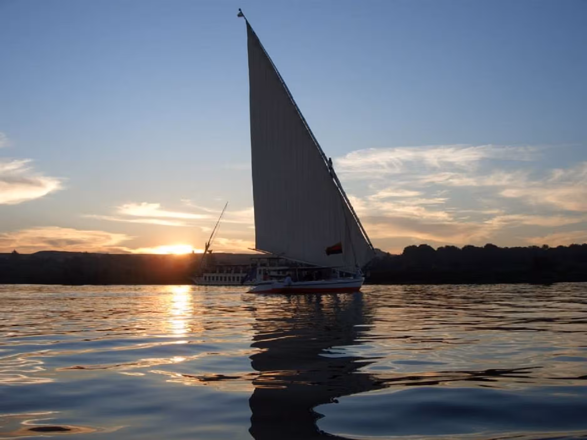 Traditional felucca sailboat gliding on the Nile at sunset, Egypt Explorer cruise and Red Sea tour
