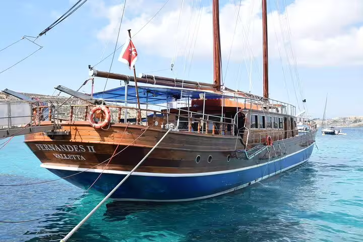 Fernandes II wooden boat from Valletta docked in crystal-clear turquoise waters during a full-day Malta boat tour
