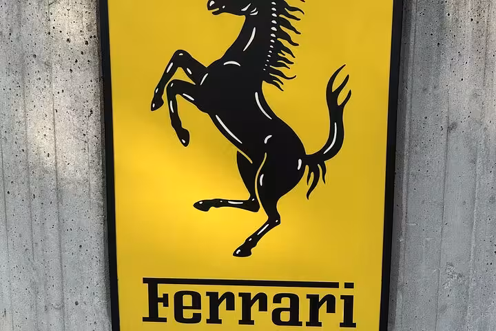 Iconic Ferrari logo with prancing horse on yellow background, featured at Ferrari Museum tour with F1 simulator experience.
