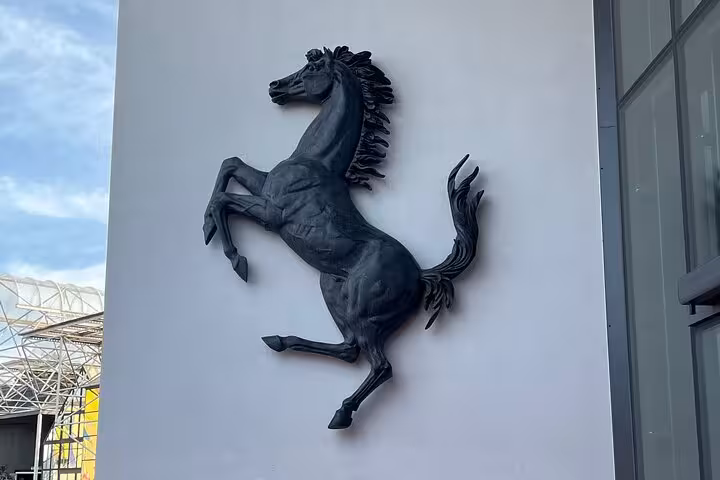 Iconic prancing horse emblem on Ferrari museum wall, included in small group tour with lunch and luxury car experiences.