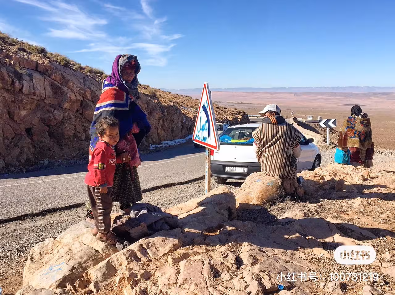 Local family near a scenic road in the Atlas Mountains on a 4-day Fes to Errachdia desert tour.