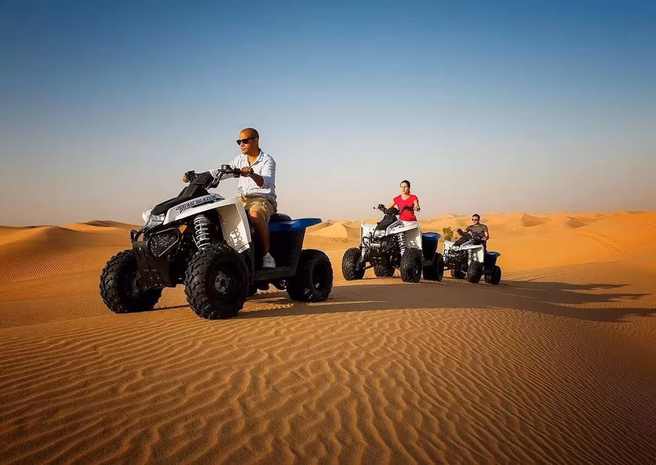 Adventurous tourists riding quad bikes across the expansive Merzouga desert dunes on a 4-day tour from Fes.