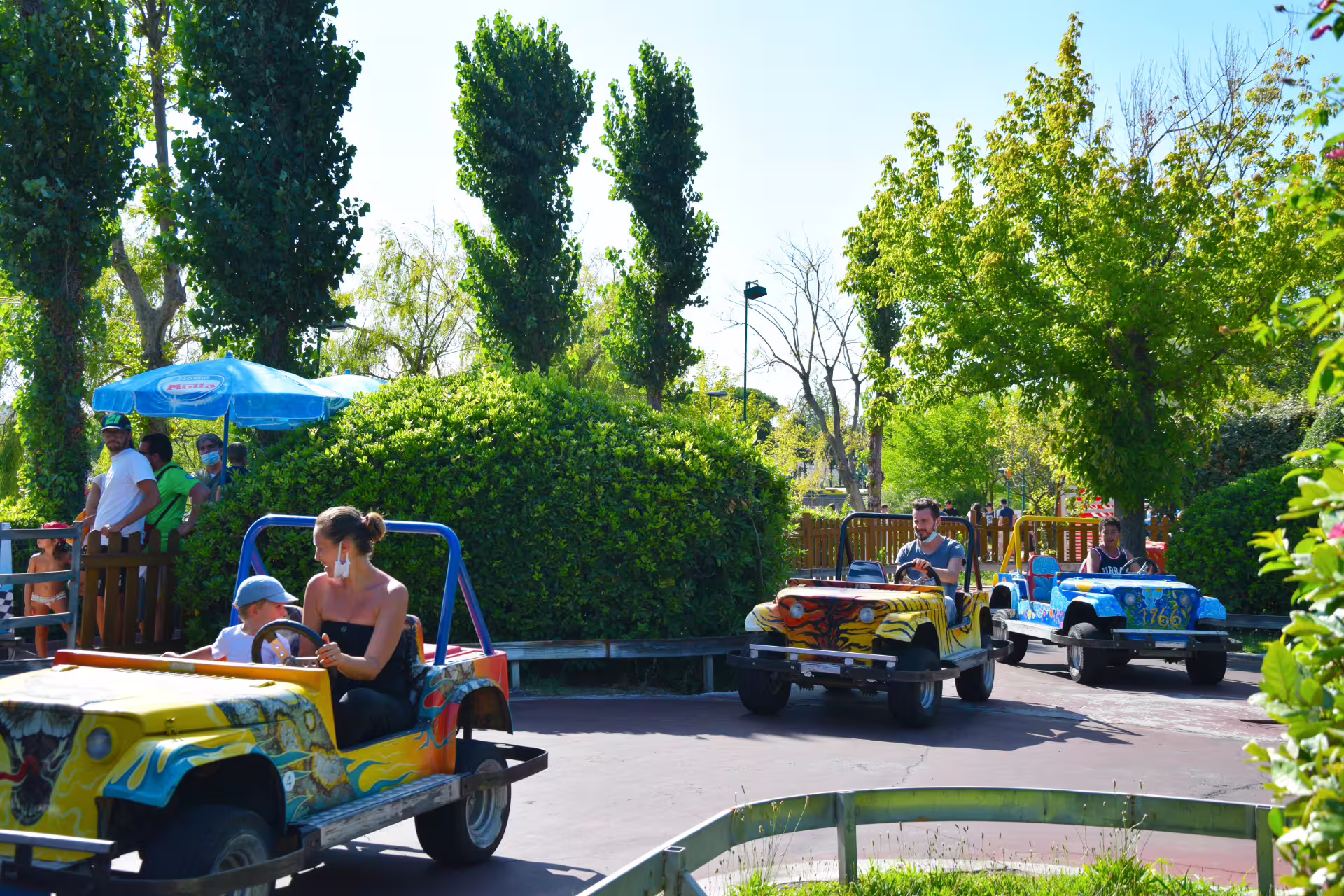 Family driving colorful mini cars on Fiabilandia kids ride in Rimini amusement park with entrance ticket