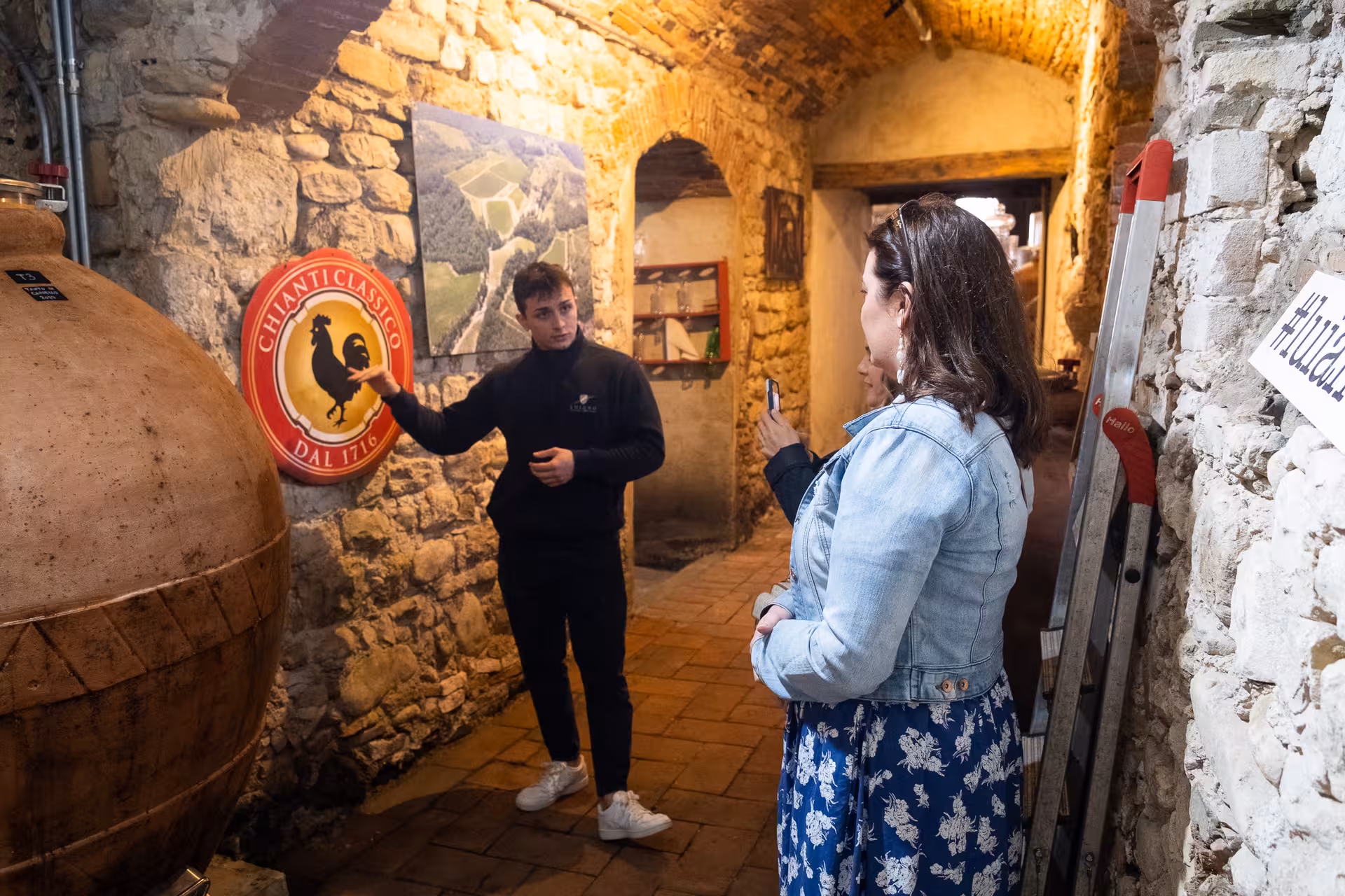 Tourists enjoying an olive oil tasting and tour in a rustic Tuscan farm cellar.