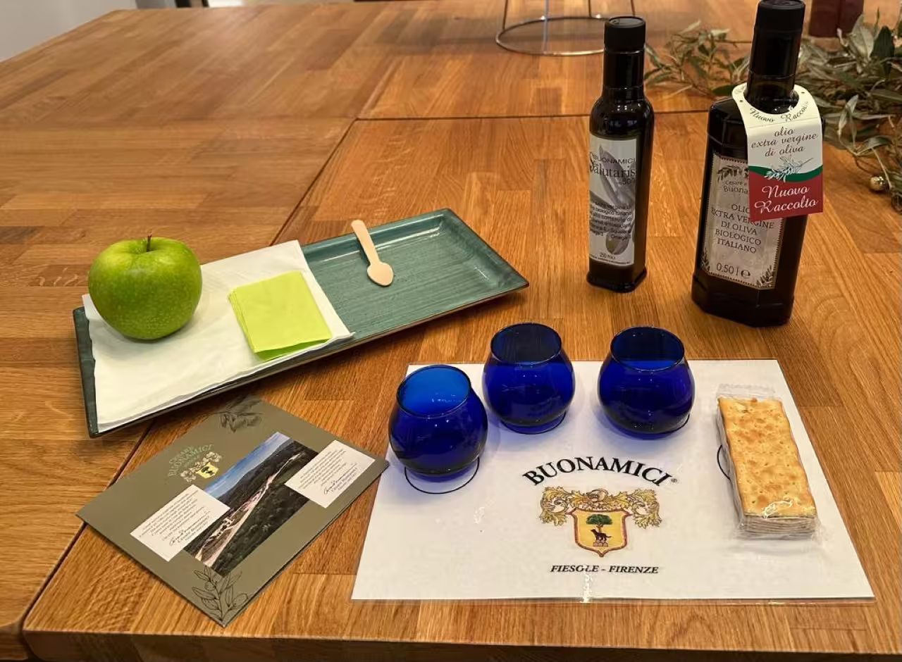 Olio EVO tasting setup at Frantoio Buonamici Fiesole with blue glasses, bread, and extra virgin olive oil