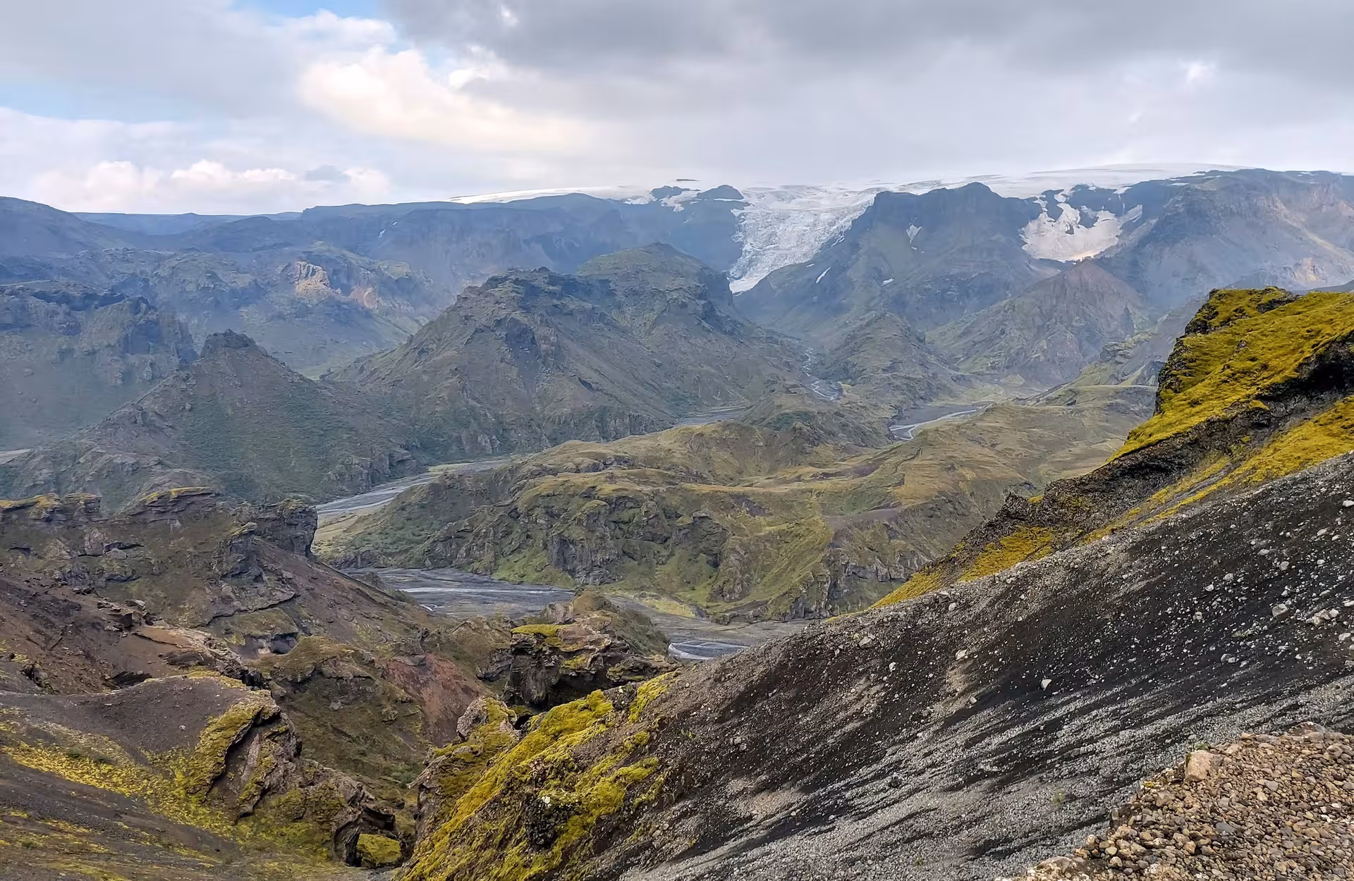 Sweeping valley view with moss-covered volcanic rocks and glacier on Fimmvorduhals hike in Iceland