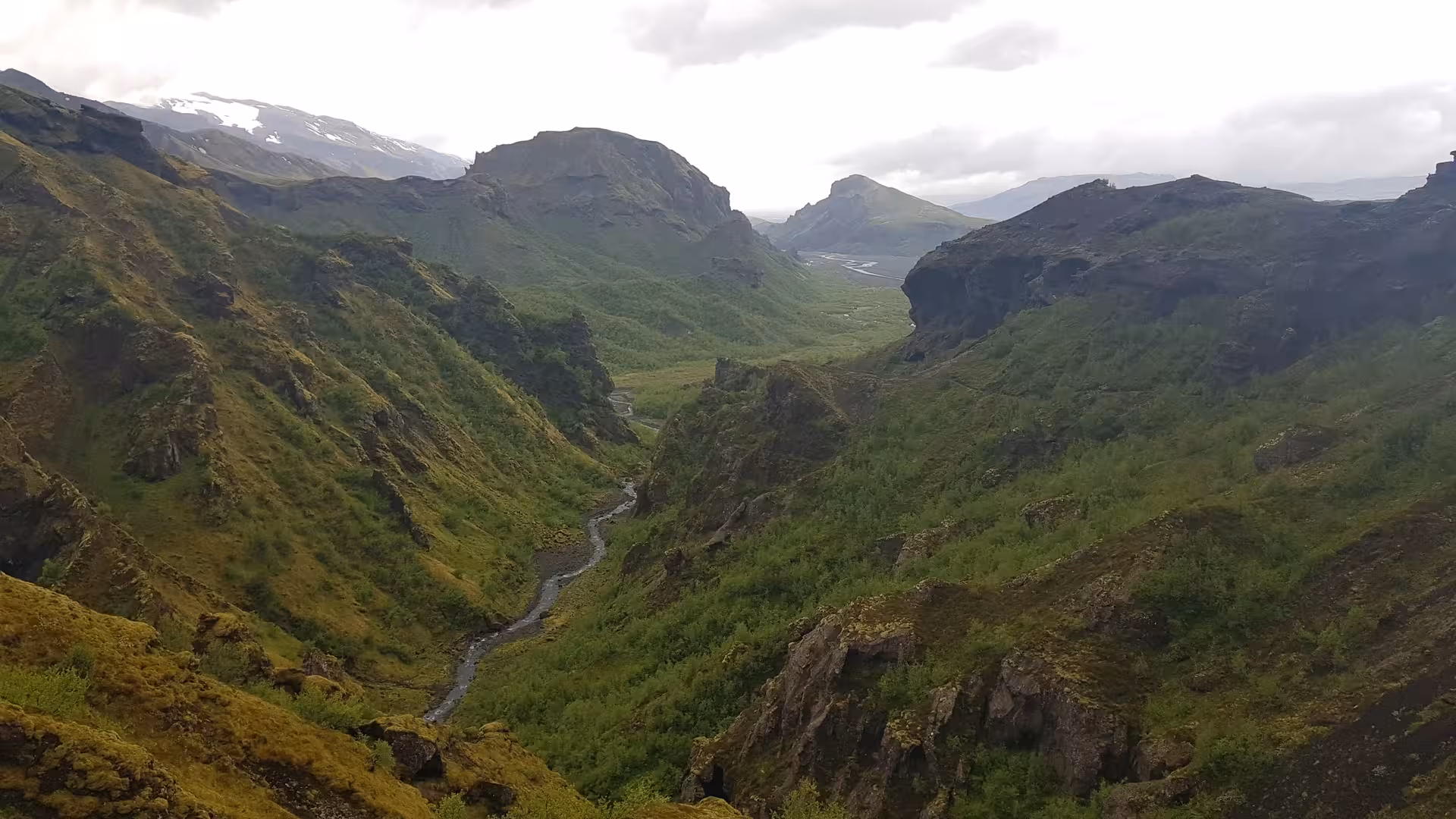 Lush green valley with winding river and volcanic mountains on Fimmvorduhals hike in Iceland