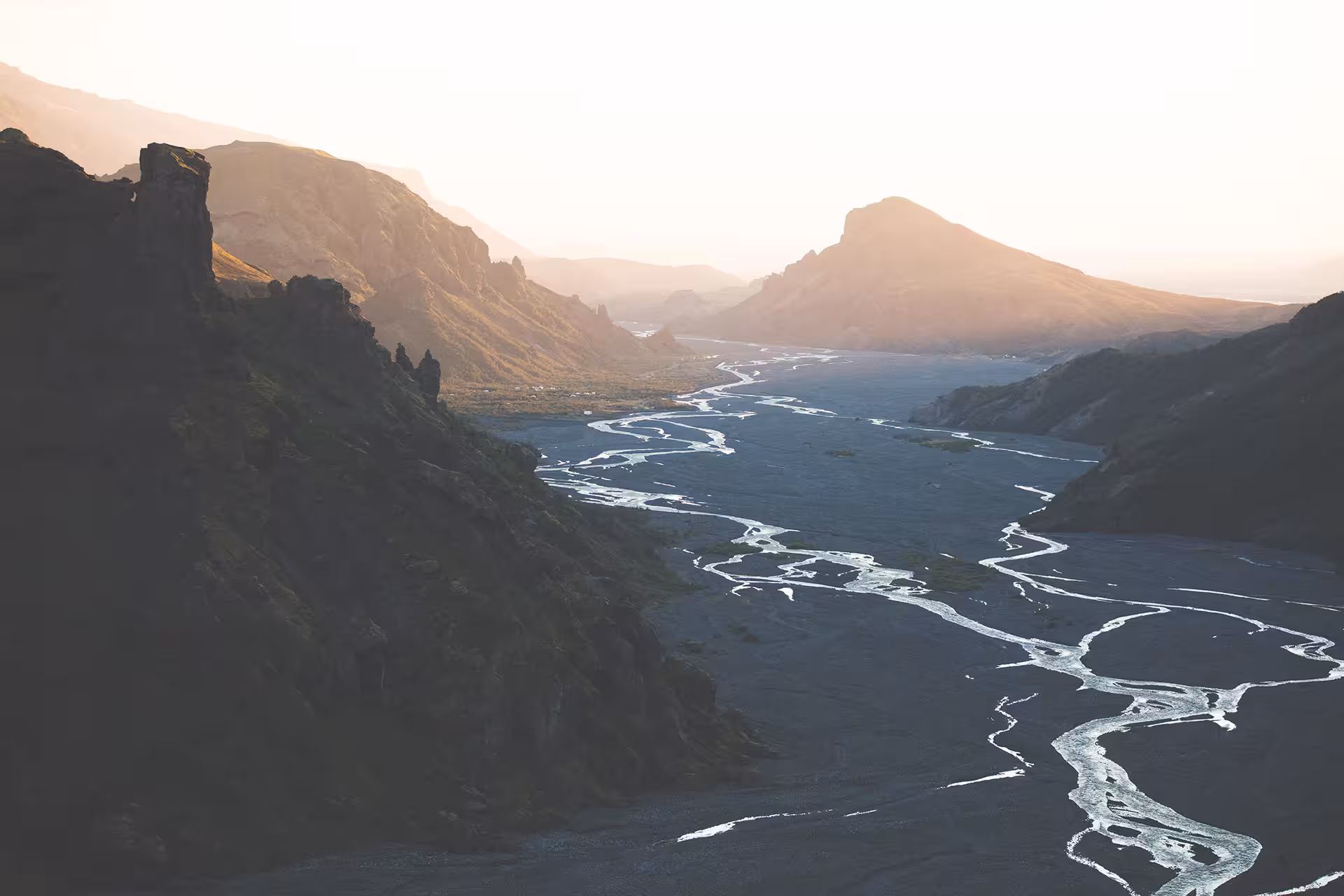 Braided glacial river winding through a dramatic Icelandic mountain valley at golden hour sunset