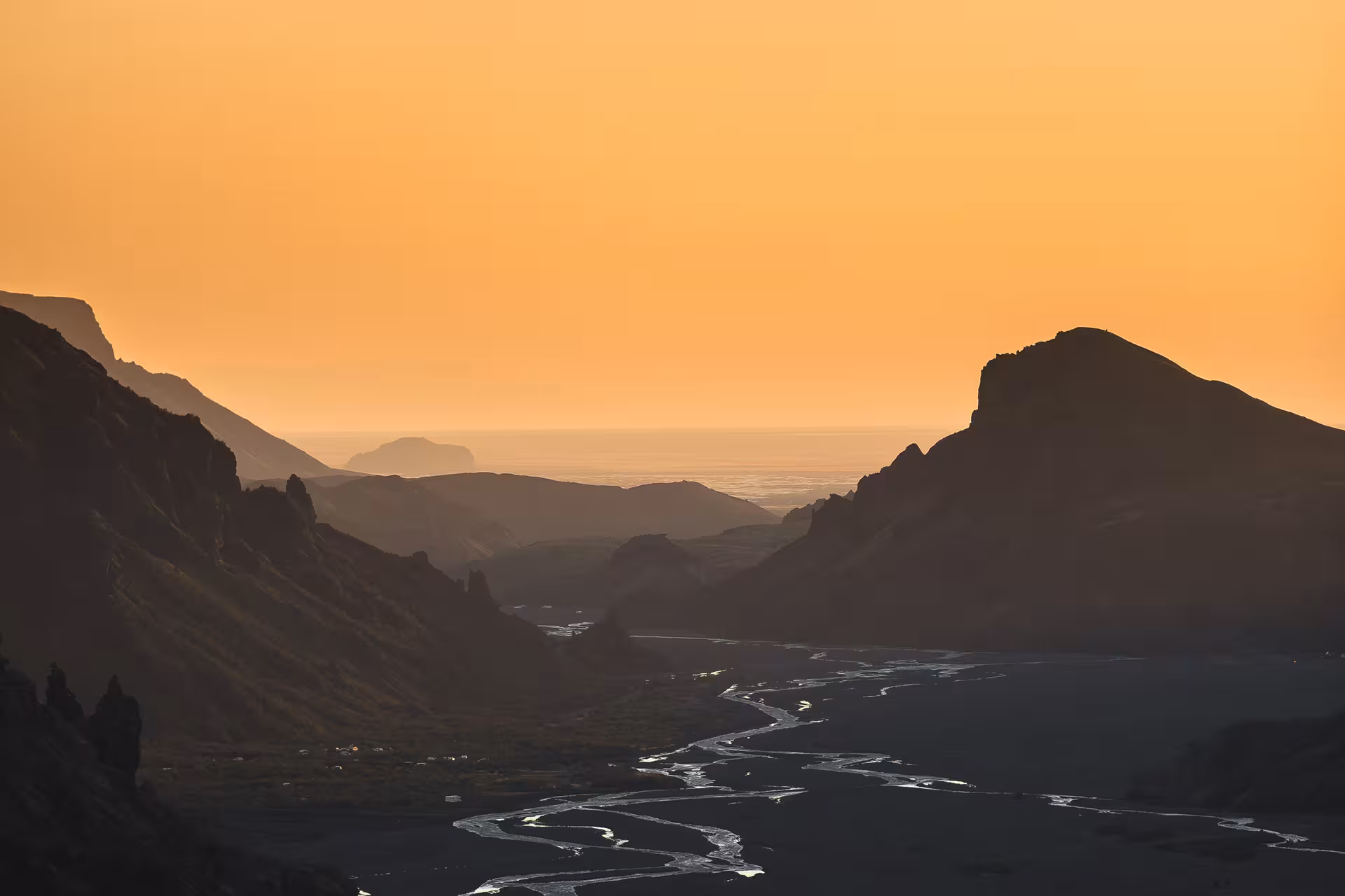 Braided glacial river winding through a mountain valley at golden sunset in Iceland