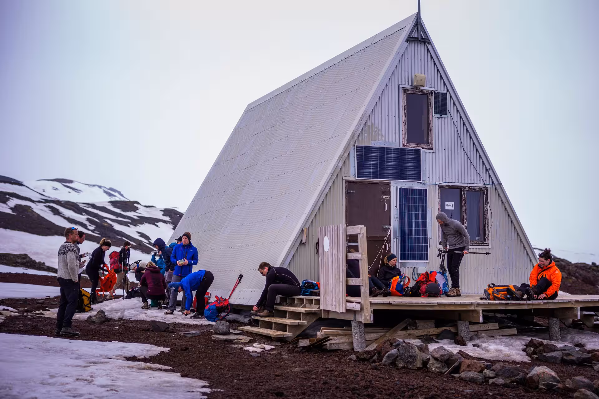 Hikers resting at an A-frame mountain hut with solar panels on the Fimmvörðuháls trail in Iceland