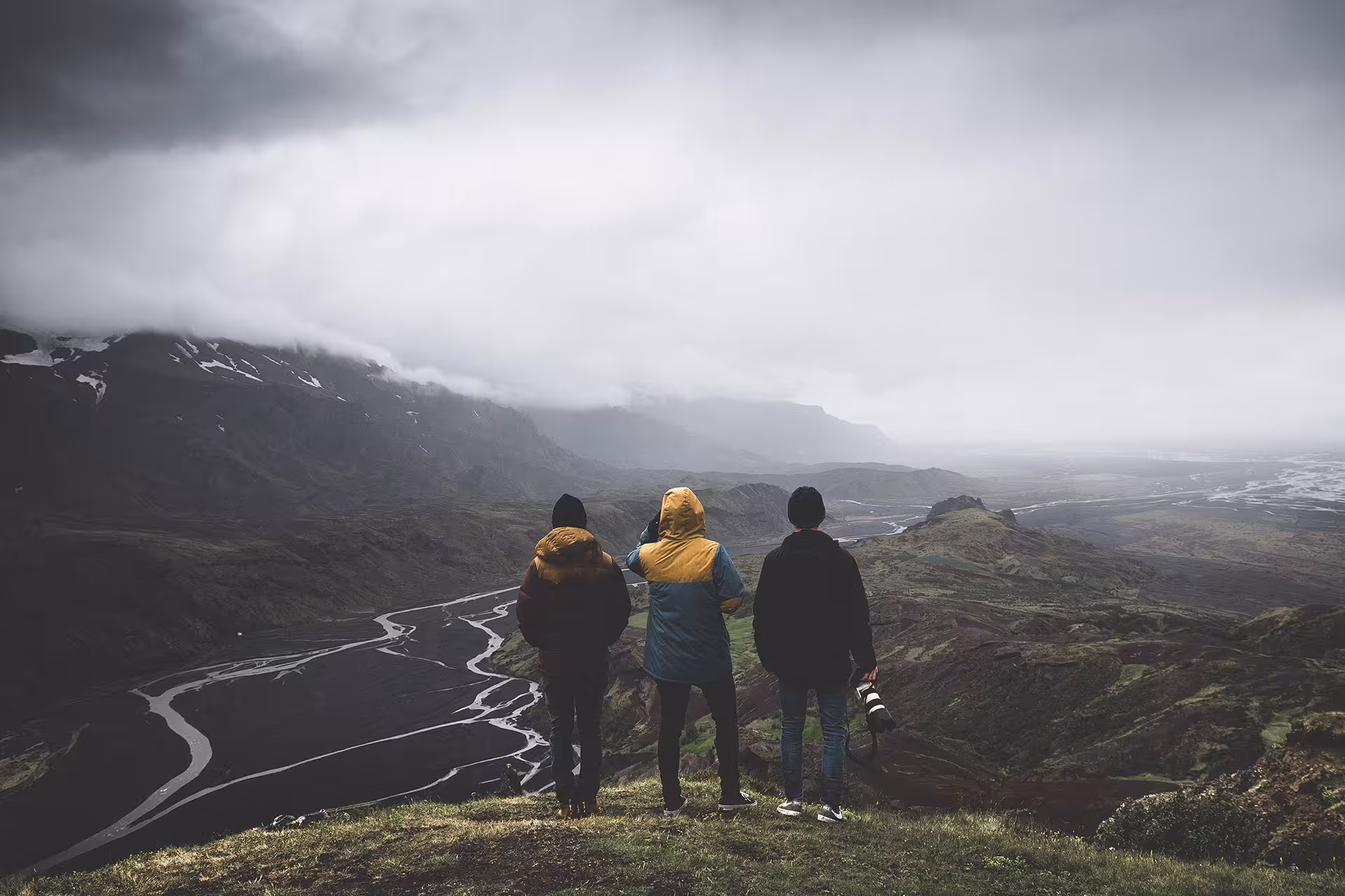 Three hikers overlooking a dramatic glacial river valley on the Fimmvorduhals trail in Iceland