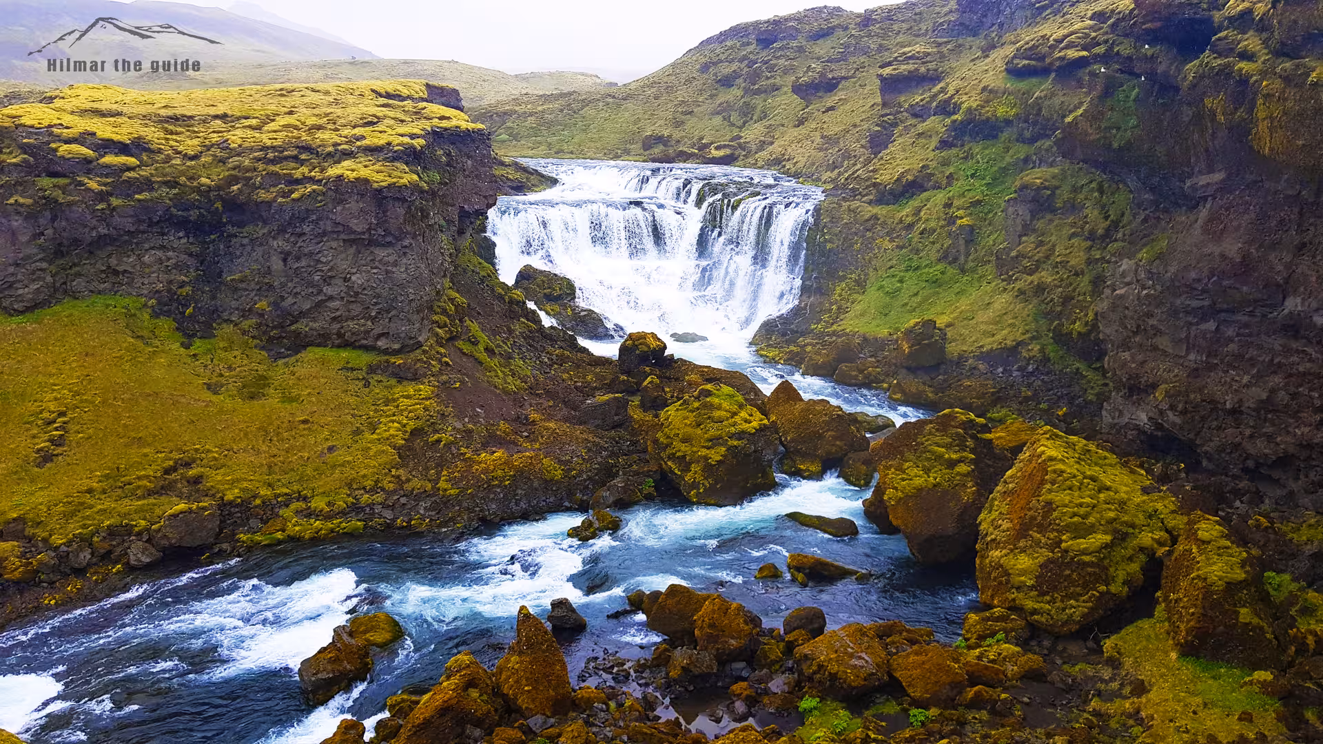 Mossy canyon waterfall flowing into turquoise river rapids on Fimmvorduhals hike in Iceland