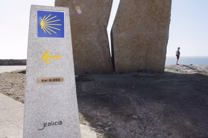 Kilometer zero marker at Finisterre, symbolizing the end of the Camino, featured on Costa da Morte tour adventures.