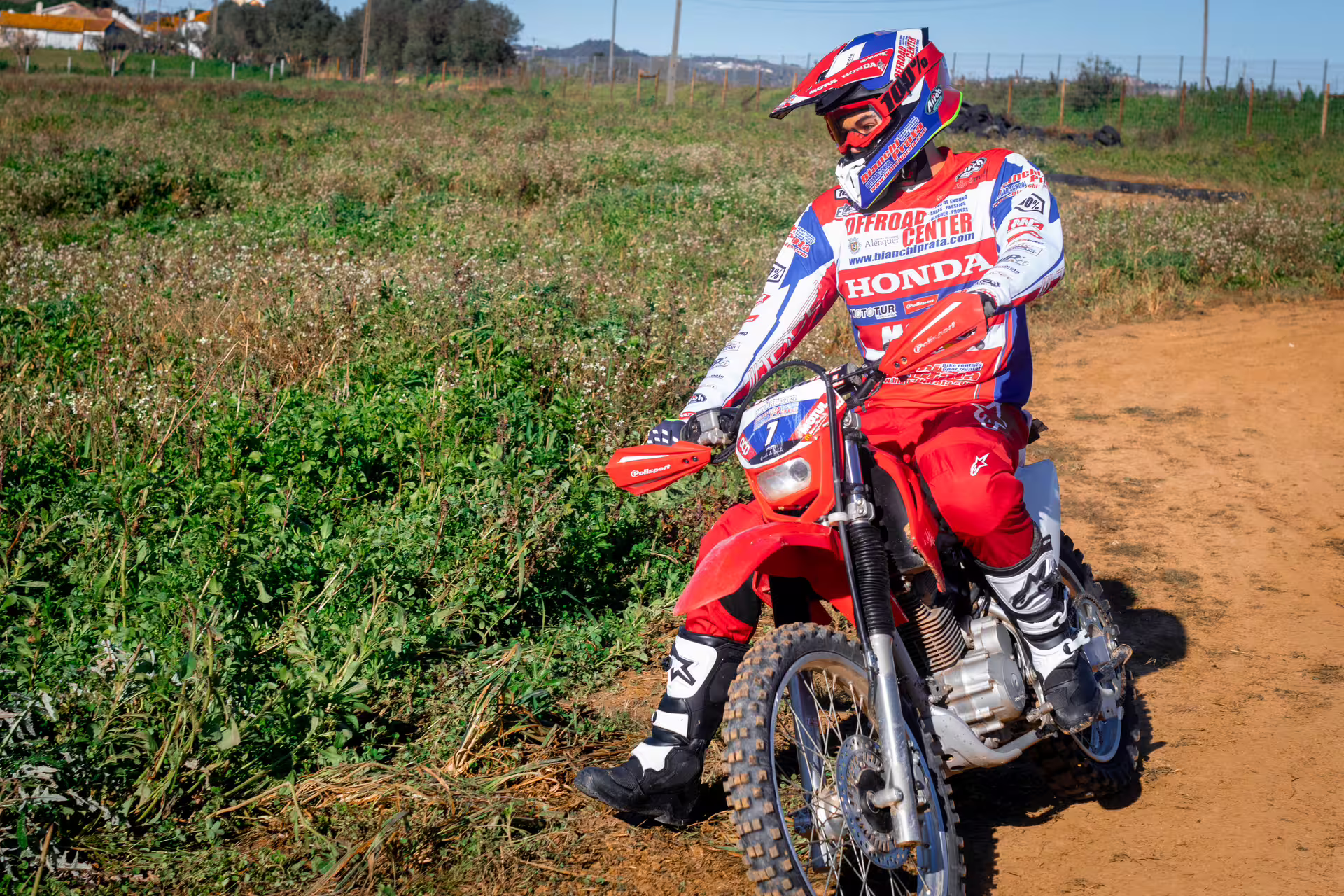 Rider in full gear on a red dirt bike exploring scenic trails during the First Ride Enduro Experience in Carregado, Lisbon.
