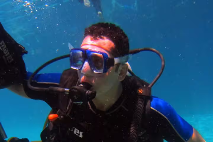 Close-up of first-time scuba diver breathing underwater in crystal-clear water on an intro diving and snorkeling trip