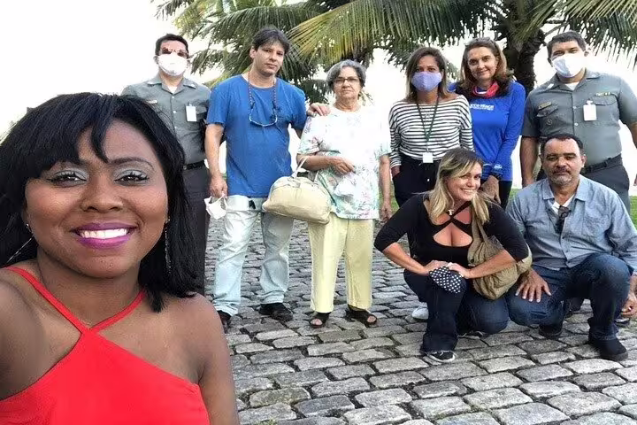 Group of tourists enjoying a moment on cobblestone street under palm trees during the Fiscal Island tour in Rio.