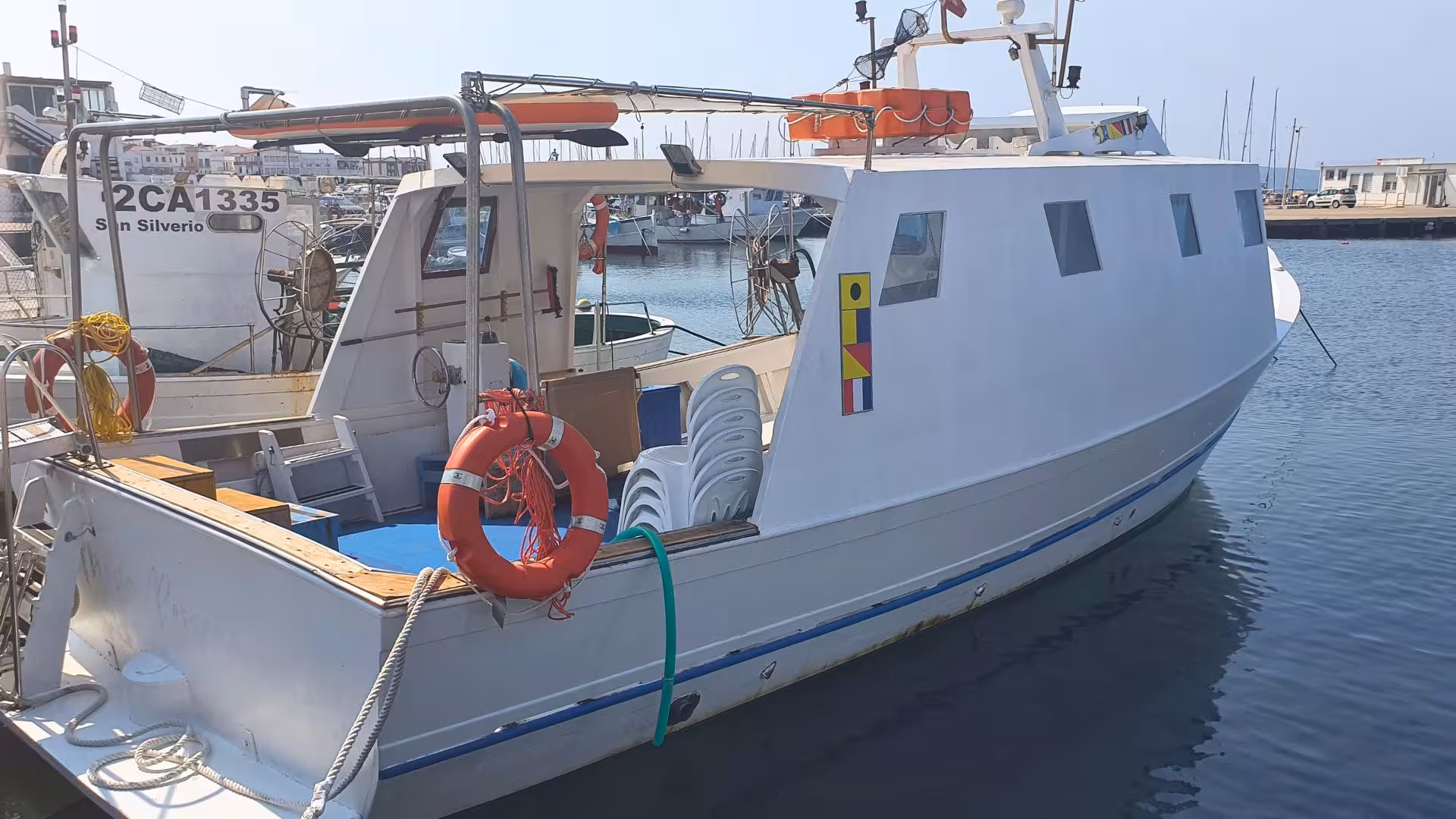 Fishing boat docked at Calasetta harbor for San Pietro Island tour, ready for a scenic maritime adventure.