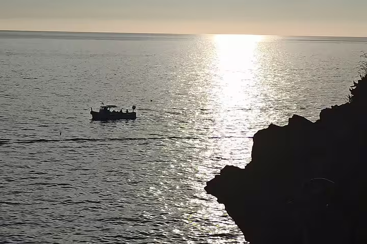 Fishing boat sailing at sunset off the rocky Cinque Terre coast, seen during transfer from La Spezia cruise port