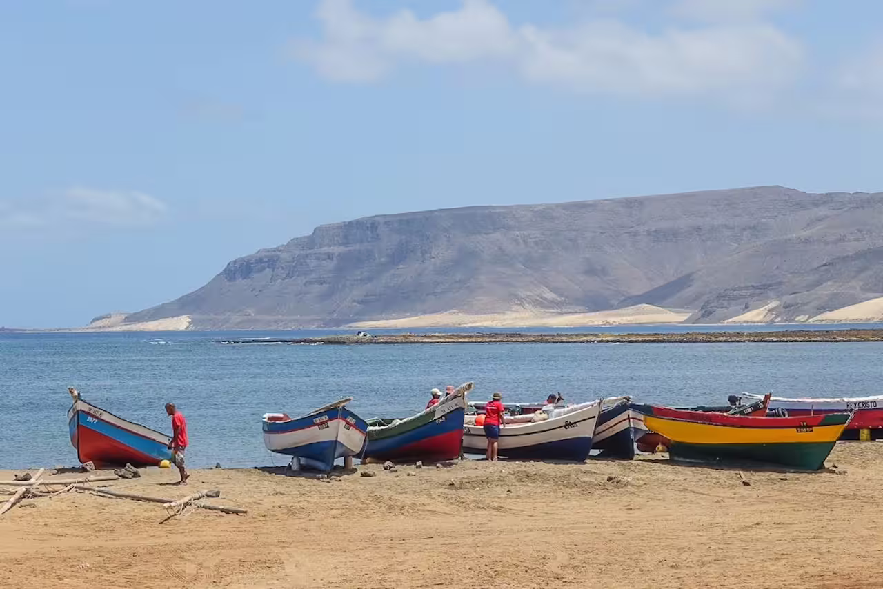 Colorful fishing boats on a sandy beach with Monte Verde in the background, São Vicente, perfect for a full-day island tour.