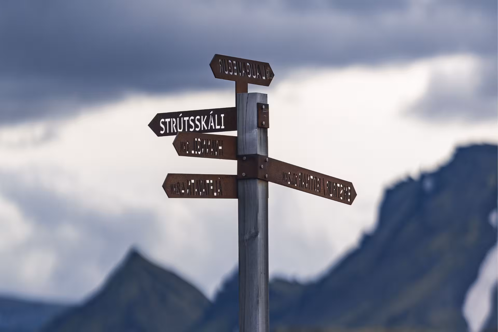 Icelandic trail signpost pointing to Strútsskáli and Laugavegur with dramatic mountain backdrop in Fjallabak
