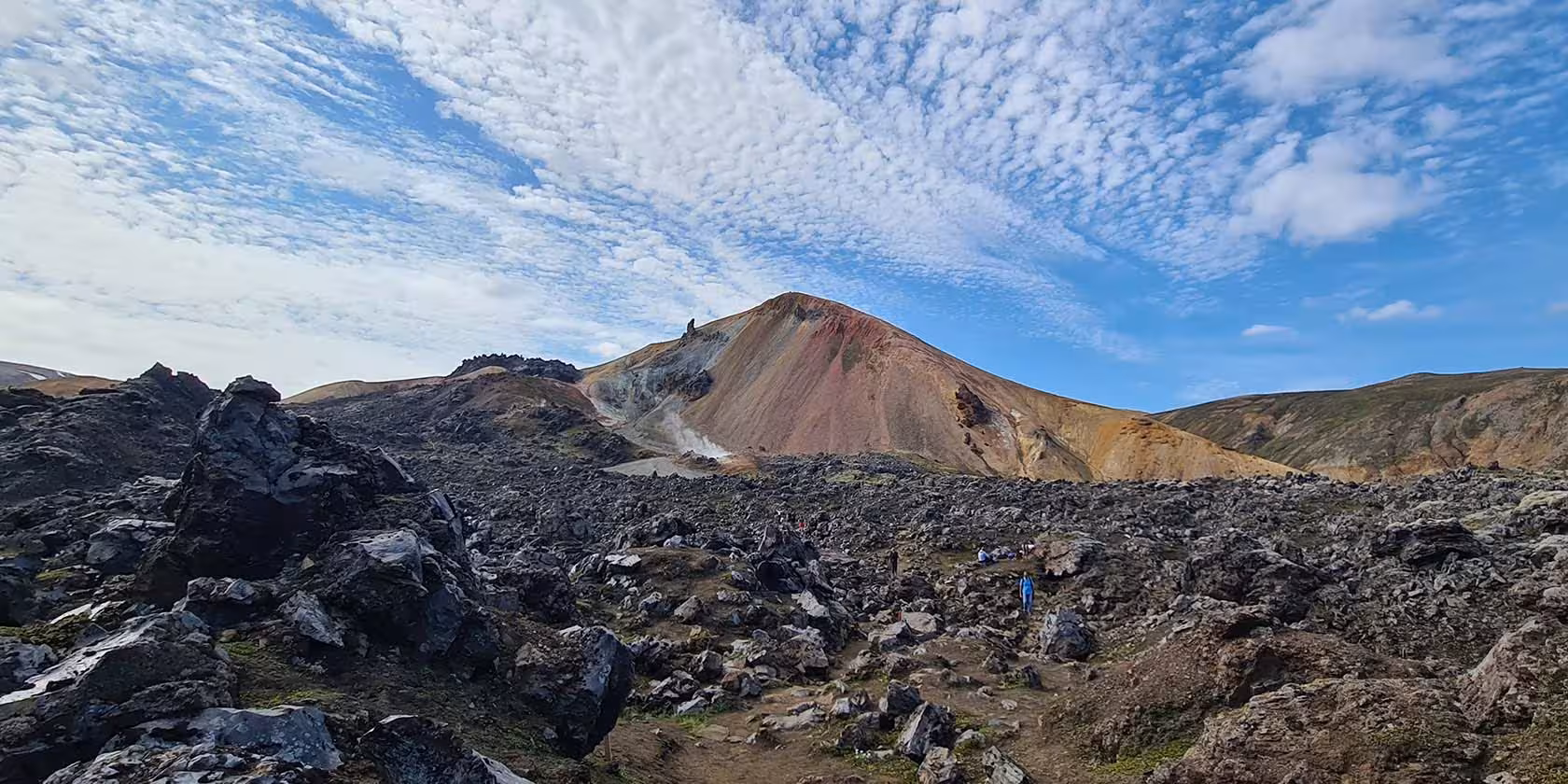 Colorful rhyolite mountains and lava fields with hikers on trail in Fjallabak Nature Reserve, Iceland