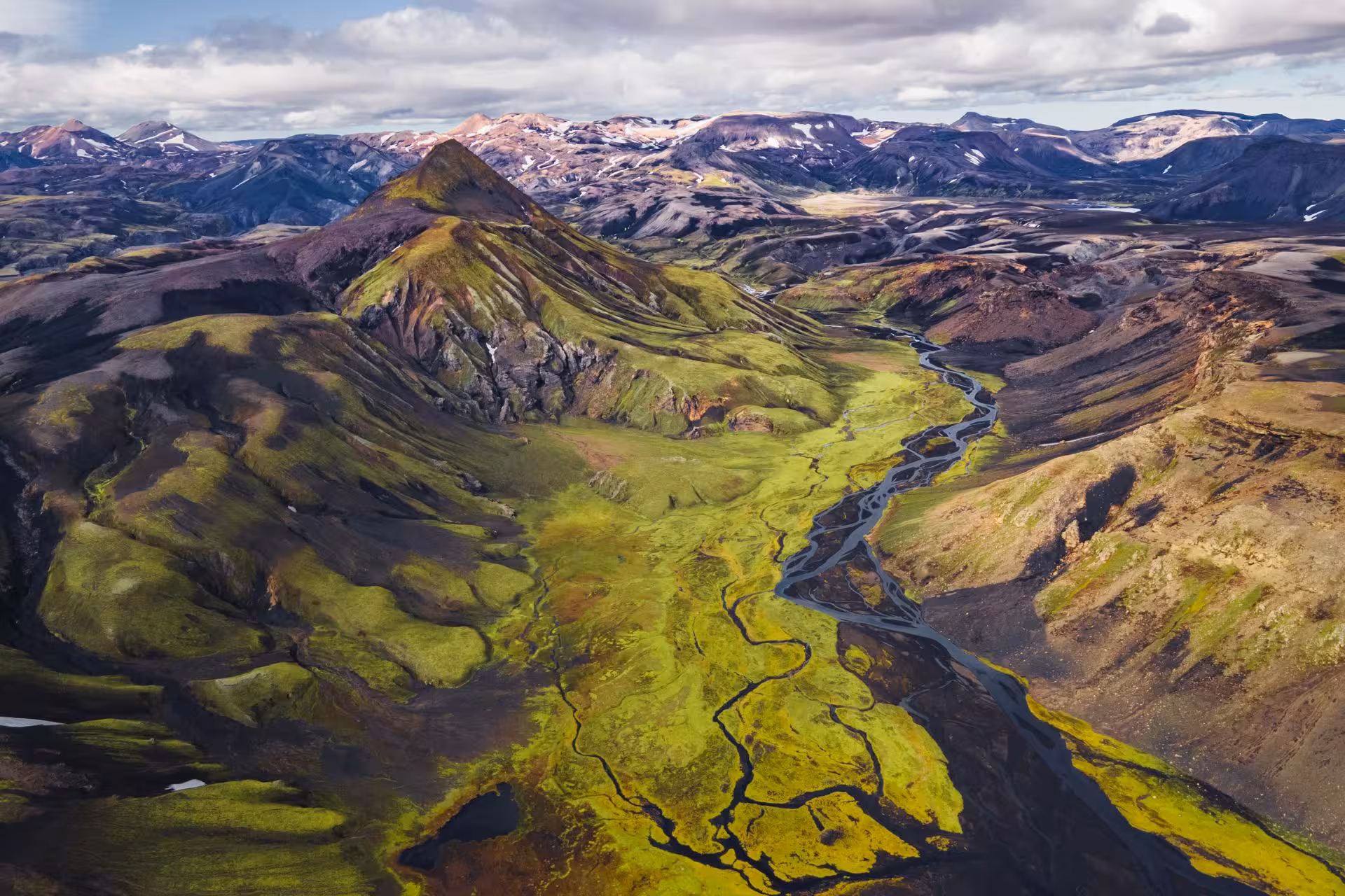 Aerial view of Fjallabak Nature Reserve with winding glacial rivers, green moss-covered highlands and colorful volcanic mountains