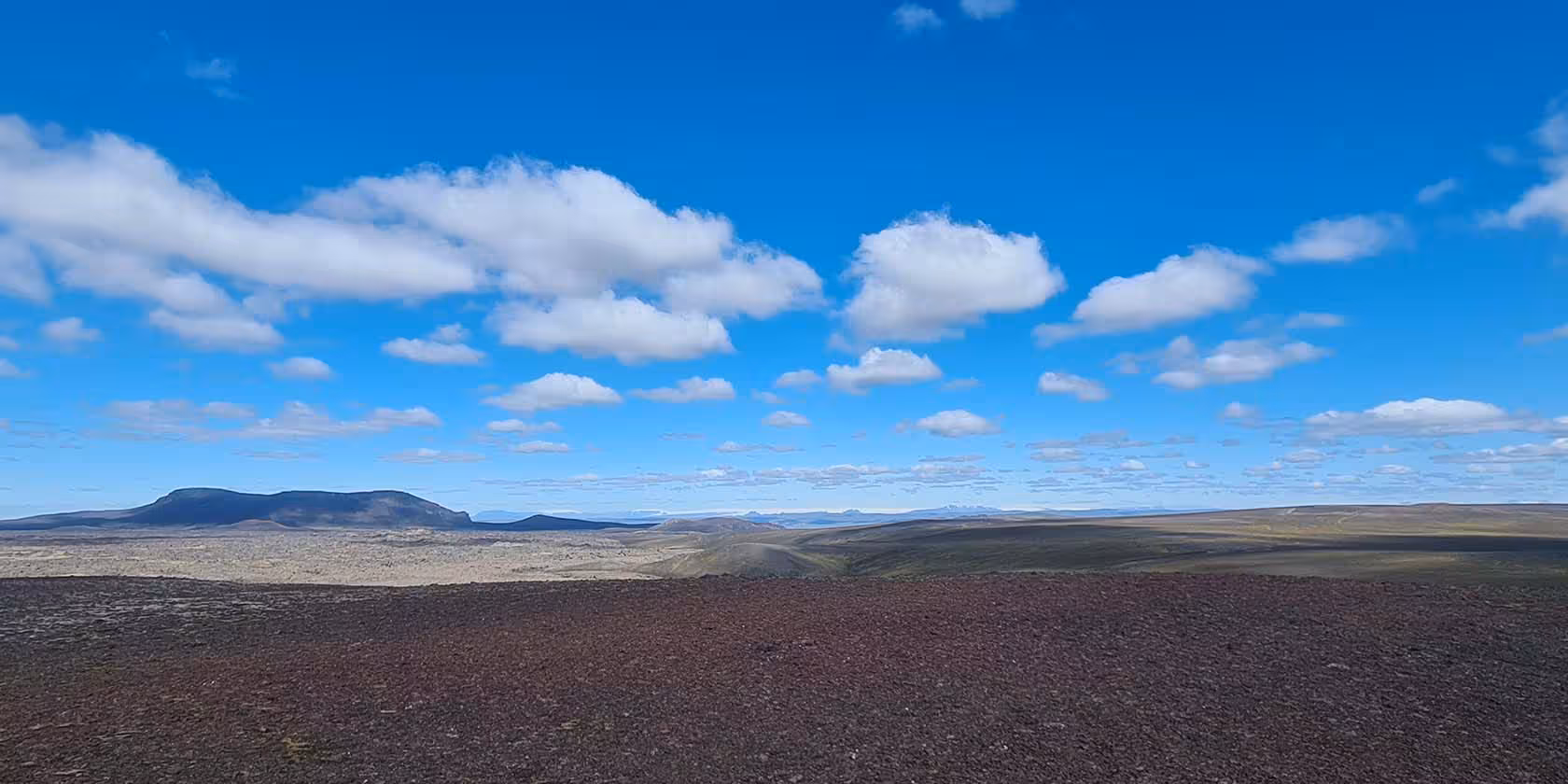 Vast volcanic lava field with flat-topped mountains and blue sky in Fjallabak Nature Reserve, Iceland